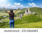 A tourist woman looks at the ruins of Corfe Castle, Dorset, England, during a sunny spring day
