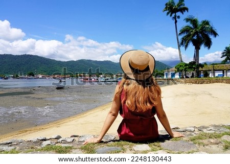Tourist woman relax peaceful sitting on wall in tropical destination