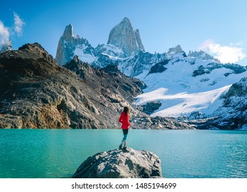 Tourist woman & scenic view of snowcapped mountain tops of Mount Fitzroy, Patagonia trek. Blue sky, turquoise blue lake and scenic rock landscape. Shot in Argentina. Nature, travel, adventure, hiking.