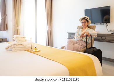 Tourist woman sitting on the chair in hotel bedroom after check-in. Conceptual of travel and accommodation.