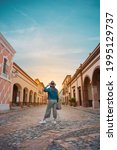 Tourist woman standing in the middle of the street of a magical town, town of La Peña del Bernal in Querétaro, Mexico, with sunset in front, summer day