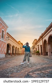 Tourist woman standing in the middle of the street of a magical town, town of La Peña del Bernal in Querétaro, Mexico, with sunset in front, summer day - Shutterstock ID 1995129737