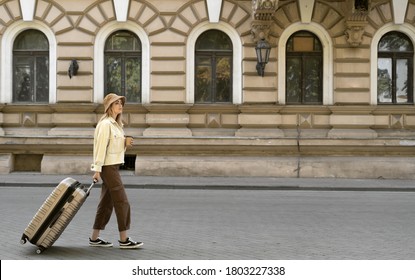 tourist woman with a suitcase down the street in a European city, tourism in Europe. walks down the street pulling luggage with him.
