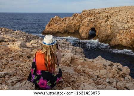 Tourist woman taking picture with her  phone at Cala es Pous bay  in Menorca island at Punta Nati area. 