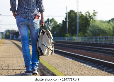 Tourist woman waiting for international train on railway station. Woman with backpack and passport in pocket travelling on Europe. 