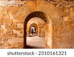 Tourist woman walking through inside vaults of the Castello Maniace. Interior of ancient citadel fortress Maniace Castle on island of Ortygia in Syracuse, Sicily, Italy, Europe EU. UNESCO Site. Tunnel