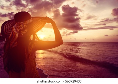 Tourist woman watching sunset at tropical ocean beach