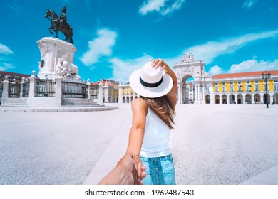 Tourist woman in white hat holding hand of her boyfriend and exploring Lisbon city together. Couple on vacation. Traveling together. Follow me. Commerce Square in Lisbon, Portugal