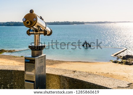 A touristic monocular aiming at the tidal swimming pool of the Bon Secours beach in the old town of Saint-Malo in Brittany, France, from the city wall at sunset.