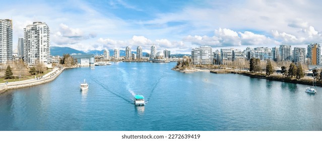 Touristic waterfront city panorama on a sunny spring day with modern highrise buildings, boats, water taxi, sunday walkers and mountain background. False Creek, Vancouver, BC, Canada. Selective focus. - Shutterstock ID 2272639419