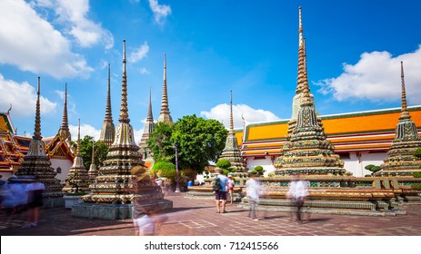 Tourists admire the many buddhist stupas at Wat Pho temple in Bangkok, Thailand (faces blurred for commercial use)