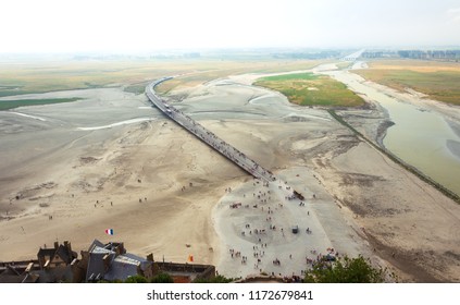 Tourists Arriving (walking,by Shuttle Bus, Or In Horse Carriage) To Visit The Famous Mont Saint Michel Abbey. France. Aerial View From The Walls Of Medieval Village. 