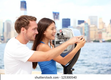 Tourists Couple Travel In New York. Beautiful Young Interracial Young Couple On Travel Looking At Manhattan And New York City Skyline From Ellis Island. Asian Woman, Caucasian Man.