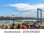 Tourists in a double-decker bus hop-on-hop-off ride through the streets of Budapest, visiting historical sights. Sunny day, perspective