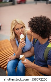 Tourists Eating Ice Cream And Sitting On A Bench.