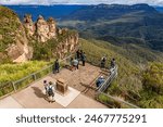 Tourists enjoy the view of the “Three Sisters” rock formation in the Blue Mountains National Park near Katoomba, NSW, Australia