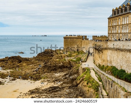 Tourists enjoying the beach surrounding the fortress of Saint Malo during low tide, Brittany, France
