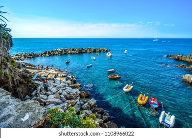 Tourists gather at a small harbor in Riomaggiore, Italy filled with rafts and boats on the Ligurian coast at Cinque Terre