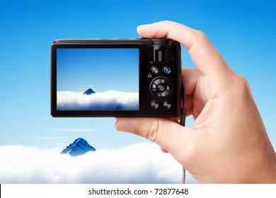 Tourist's hand holding photo camera, taking picture of beautiful mountain landscape