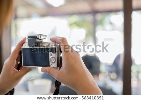 Tourist's hand holding photo camera, taking picture in coffee shop
