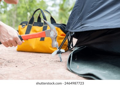 Tourists' hands use hammers to hammer into the ground to make the tents strong. - Powered by Shutterstock