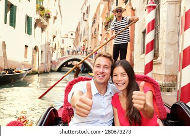 Tourists Happy Couple Traveling In Venice Gondola Giving Thumbs Up Hand Sign Joyful On Travel. Romantic Young Beautiful Couple On Vacation Holidays Sailing In Venetian Canal In Gondole. Italy