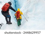 Tourists helping each other and climbing down the glacier crevasse using ropes. Exit Glacier ice hiking. Alaska. 