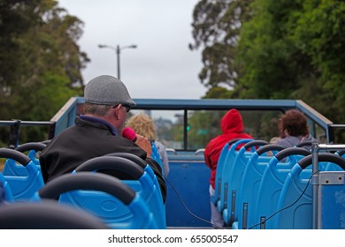 Tourists And A Host On A Hop On Hop Off Open Top Bus