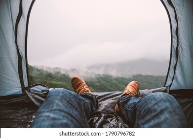Tourists lay in tents, looking outside the tent to see the foggy mountains after the rain, Focus on shoes.