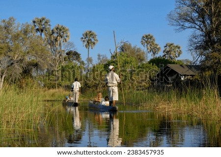 Tourists in a mokoro or dugout boat on safari in swamp area, Gomoti Plains Camp, Gomoti Concession Area, Okavango Delta, Botswana