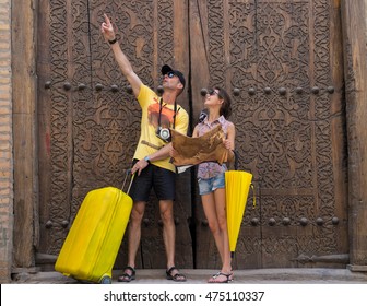 Tourists On A Background Of Carved Wooden Gate In Uzbekistan, Khiva.