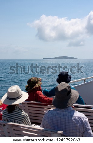 Tourists on a boat on a cruise looking at an island in a distance on the way to the Great Keppel Island in Queensland, Australia