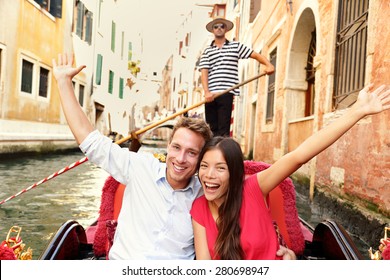 Tourists On Travel Happy Couple In Venice Gondola Cheering Excited Joyful On Travel. Romantic Young Beautiful Couple On Vacation Holidays Sailing In Venetian Canal In Gondole. Italy. Asian Woman.