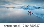 Tourists people sail on boat in Antarctica. Zodiac boat gently glides on waters surface in sunset light. Antarctica travel and exploration. Discover the beauty of South Pole. Aerial winter landscape