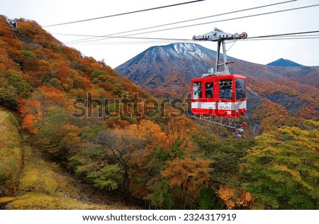 Tourists ride in Akechidaira Ropeway, enjoying a panorama of mountains blanketed with vibrant fall colors and the mountaintop of Nantai sprinkled with snow, in Nikko National Park, Tochigi, Japan