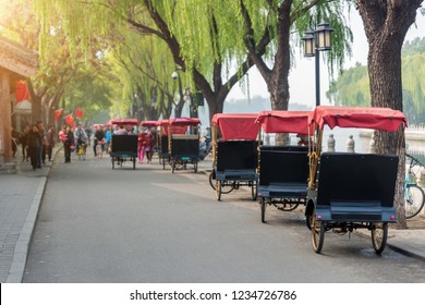 Tourists Riding Beijing Traditional Rickshaw In Old China Hutongs In Beijing, China. Landscape And Culture Travel, Or Historical Building And Sightseeing Concept