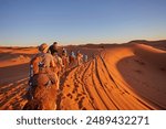 Tourists riding camels, smiling, in the Sahara Desert, Morocco.