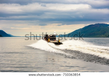 Tourists speedboating on a RIB boat (perhaps hoping to find Nessie the Loch Ness Monster) on the iconic Loch Ness, Scotland