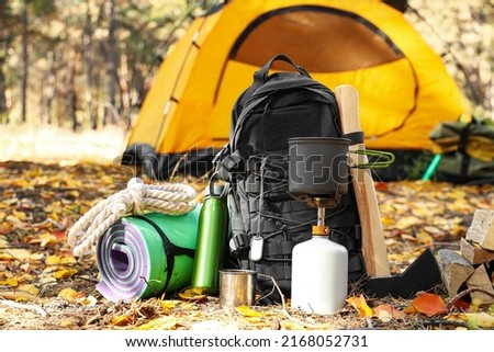Tourist's survival kit and camping tent in autumn forest