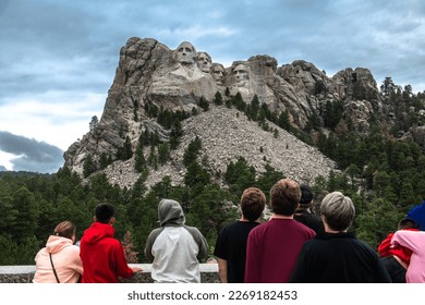 Tourists taking pictures and observe mountain Rushmor with USA presidents sculptures.