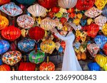 Tourists in traditional Vietnamese clothing look at lanterns in Hoi An ancient town. Traditional Vietnamese culture and lanterns at Hoi An ancient city Vietnam