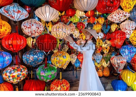 Tourists in traditional Vietnamese clothing look at lanterns in Hoi An ancient town. Traditional Vietnamese culture and lanterns at Hoi An ancient city Vietnam