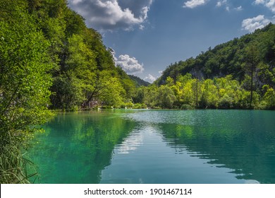 Tourists walking on footpath under trees with a view on turquoise lakes and waterfalls. Plitvice Lakes National Park UNESCO World Heritage, Croatia
