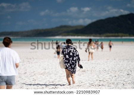 tourists walking on the white sand beach in queensland Australia, during summer at the great barrier reef