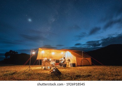 Tourists in yellow tent camping on hill with milky way in the night sky at national park