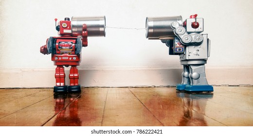 tow retro robots talk on tin can phones on an old wooden floor with reflection