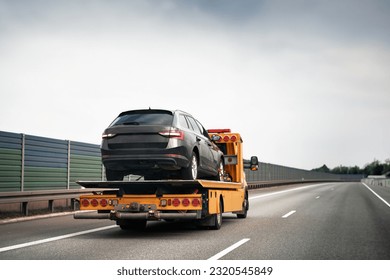 Tow truck with broken car on country road. Tow truck transporting car on the highway. Car service transportation concept. - Shutterstock ID 2320545849