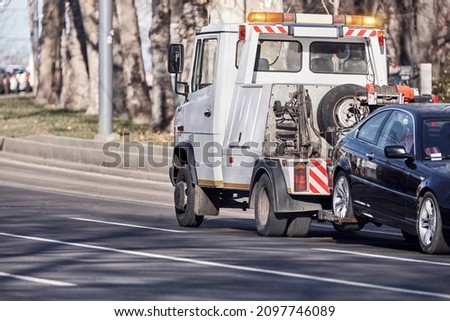Tow truck carrying improperly parked car or repossessed vehicle.