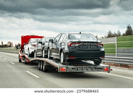 Tow truck with a cars on the highway road. Tow truck transporting car on the autobahn. Car service transportation concept. Roadside Rescue.