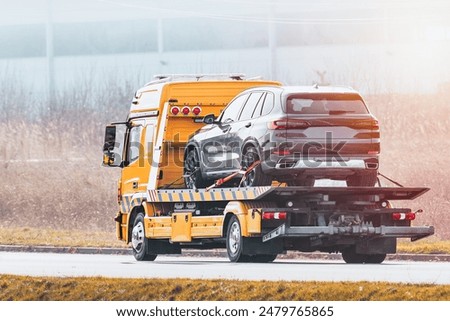 Tow truck delivering broken car on highway